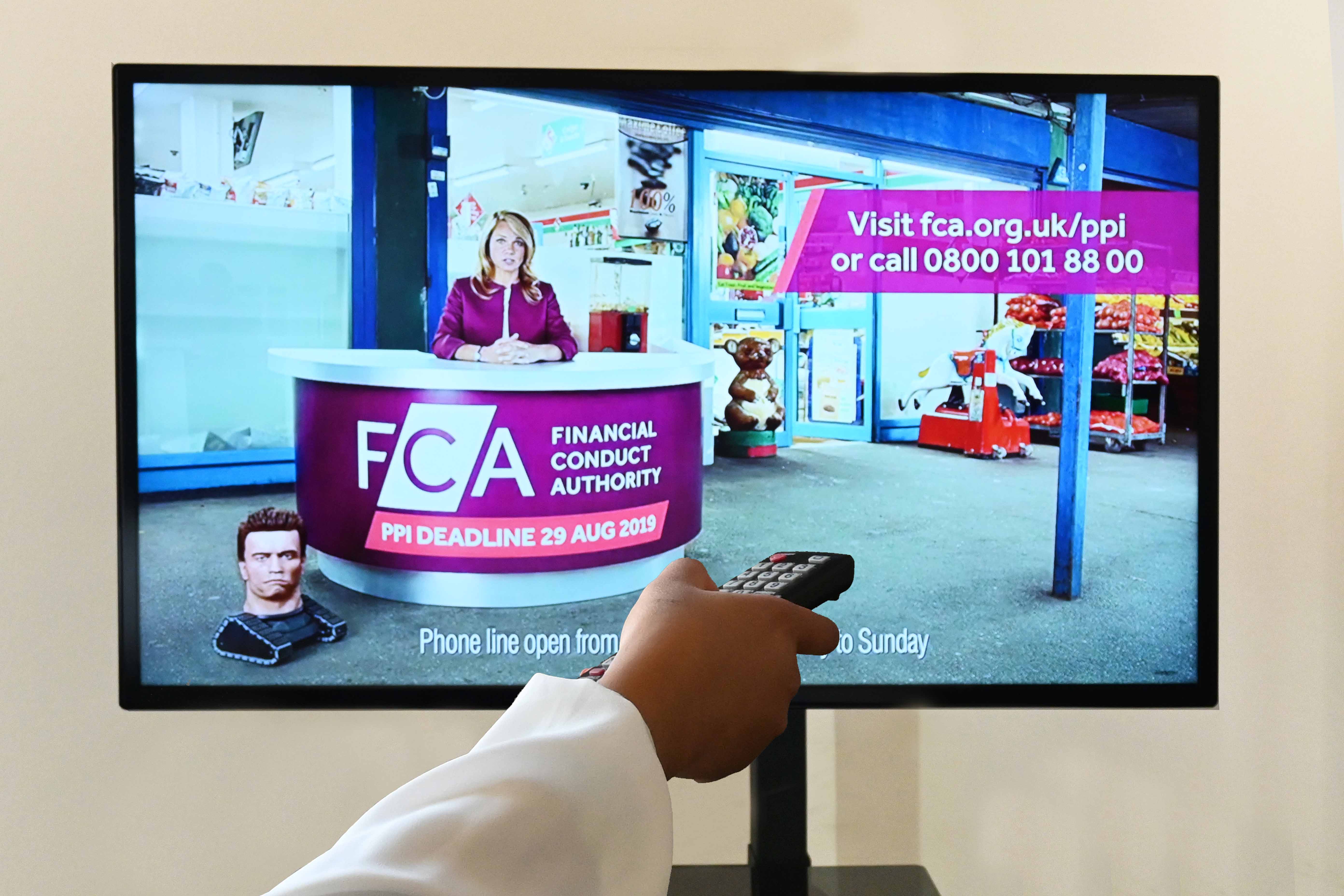 A woman points a remote at the TV. On the screen, there's an FCA advert reminding people of the deadline to claim for PPI refunds. There is a robot Arnold Schwarzenegger head in the corner of the advert, about to roll across towards the centre of the screen. 