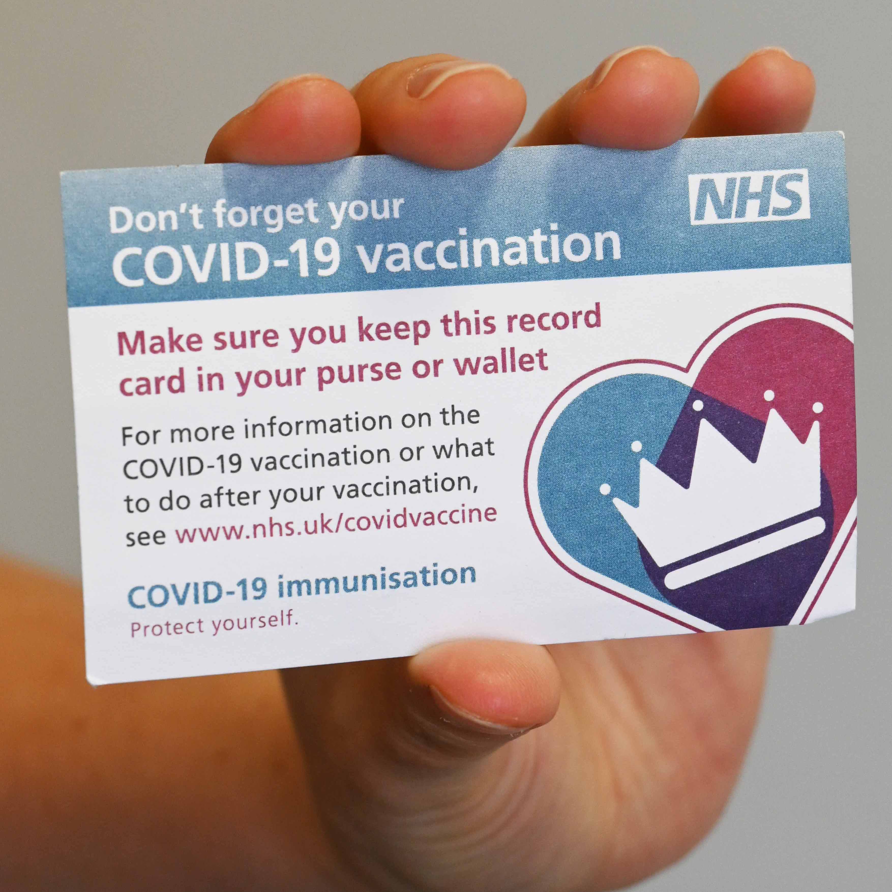 A close up shot of a person holding a COVID-19 vaccination card.