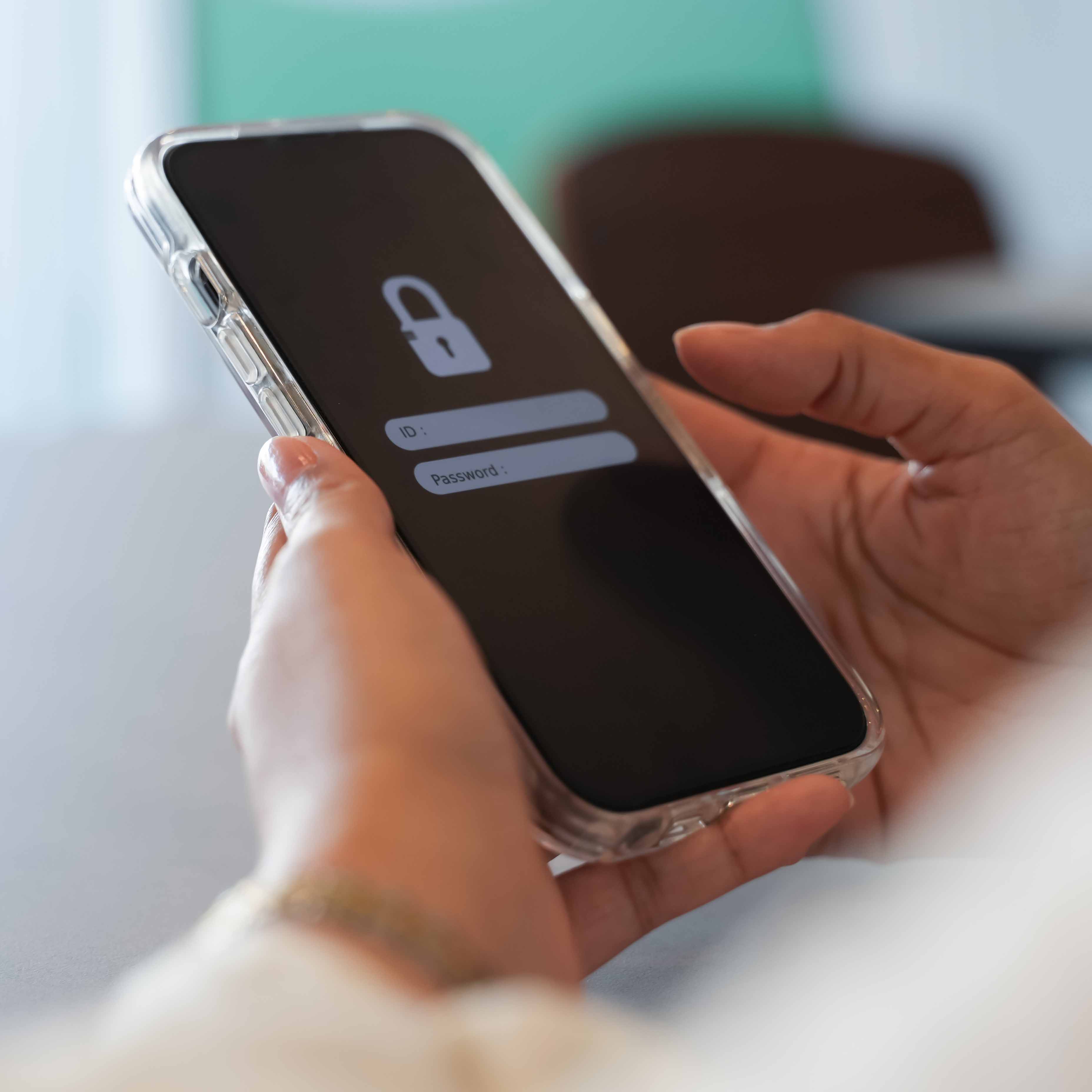 A person is holding a mobile phone in their hands. On the screen there’s a padlock symbol. The phone is encrypted – only those who should have access can get in.