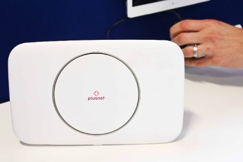 A man switches on a bright white PlusNet Wi-Fi box.