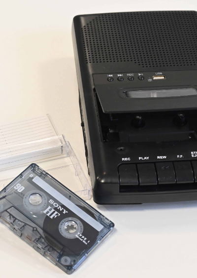 A black tape recorder is open ready for the blank tape next to it to be placed inside.