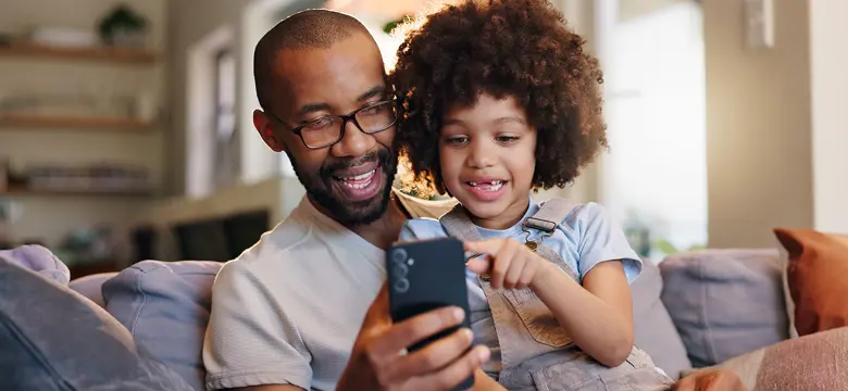A man and a young child looking at a phone