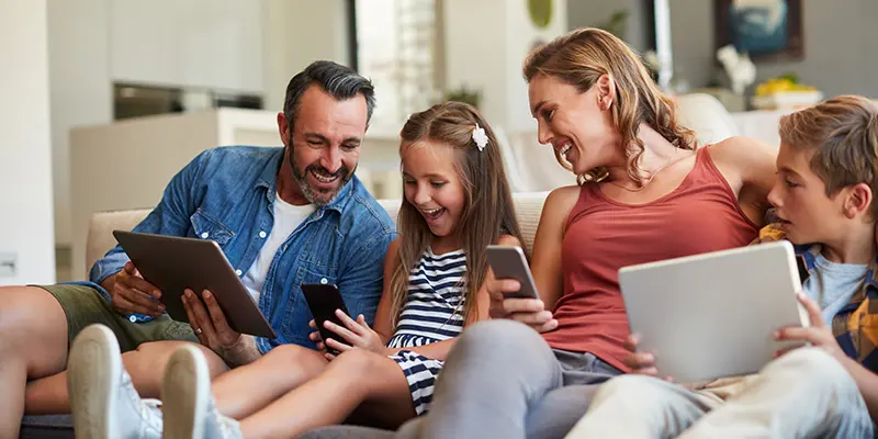 Two adults and two children looking at a mobile phone and tablet