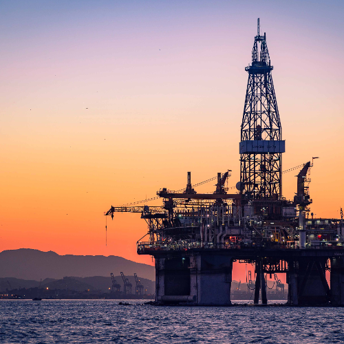 Across the backdrop of a golden sunset over the sea - an oil rig looms at the front of this photo. You can see the drill drop down into the ocean gathering millions of pounds worth of this precious commodity.