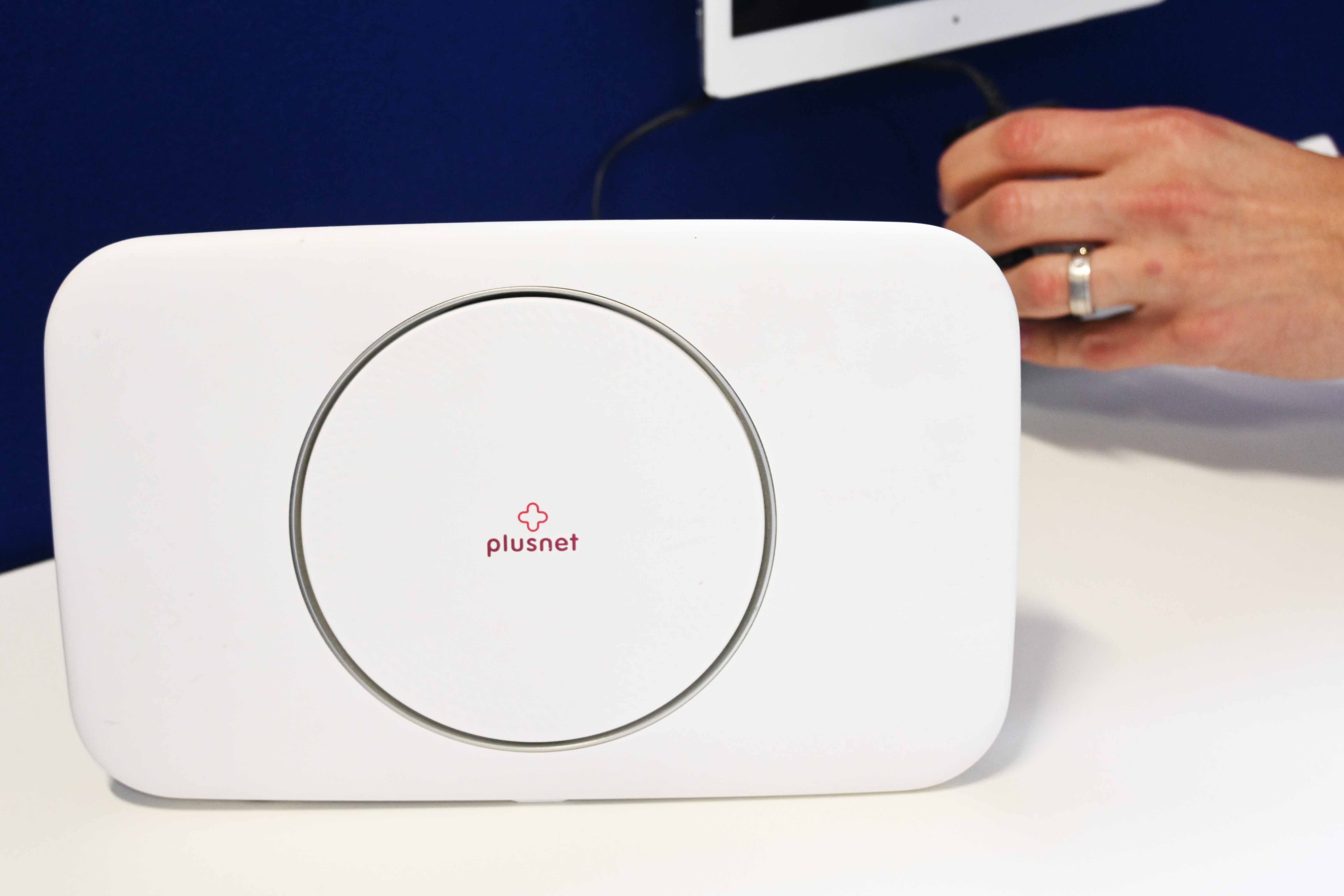 A man switches on a bright white PlusNet Wi-Fi box. 